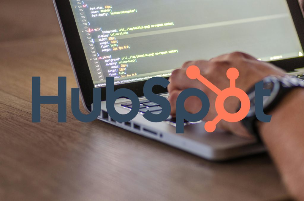 HubSpot logo over programmer's laptop screen.