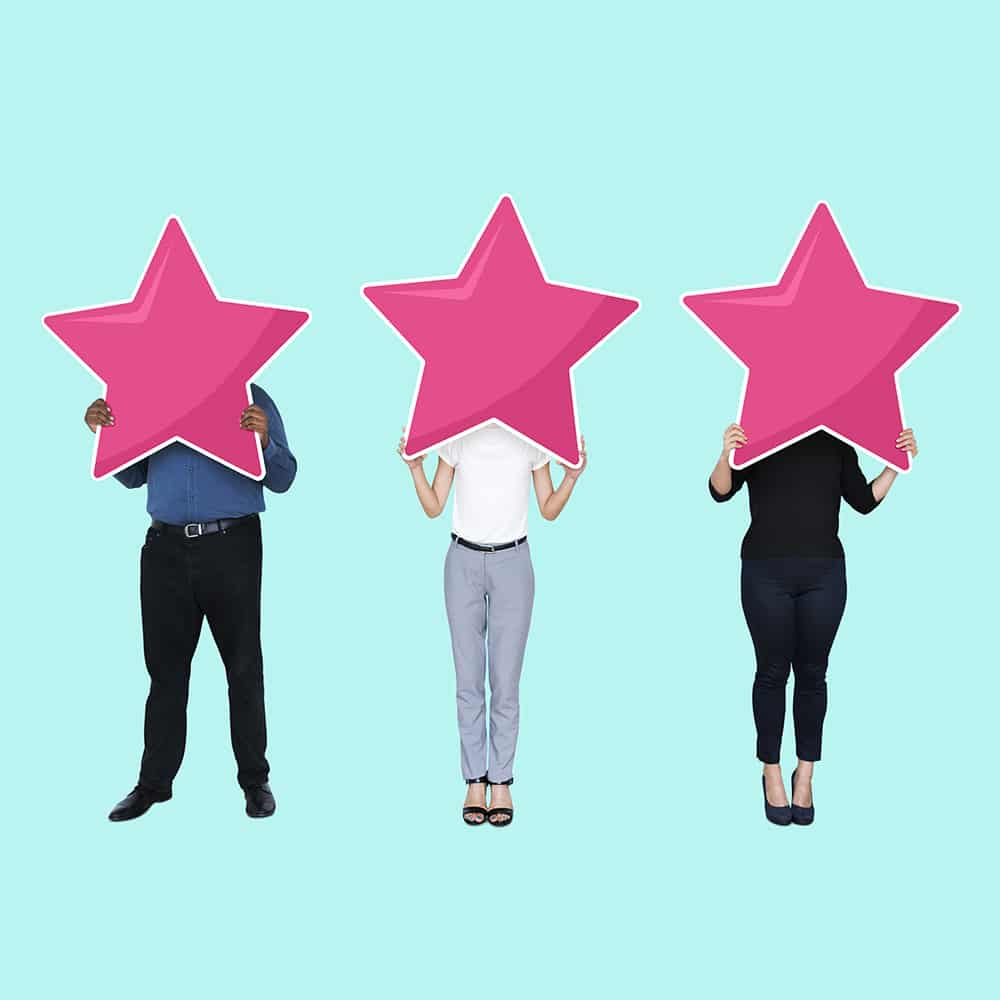Three people holding pink star cutouts over faces.