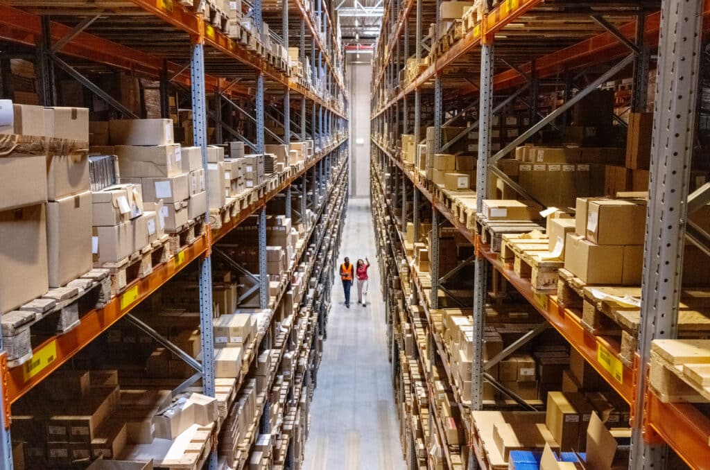 Large warehouse aisle with stacked boxes and workers